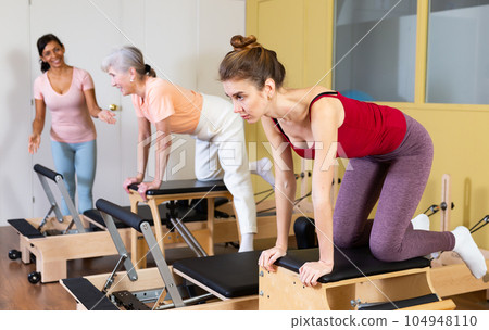 Young woman practicing pilates stretching exercises on combo chair Young woman practicing pilates stretching exercises on combo chair 104948110