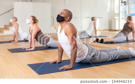 Hispanic man in protective mask performing yoga exercises 104948233