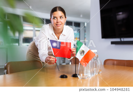 Young lady sets miniatures flags of Mexico and Taiwan for international negotiations 104948281