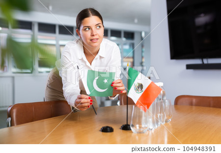 Young lady sets miniatures flags of Mexico and Pakistan for international negotiations Young lady sets miniatures flags of Mexico and Pakistan for international negotiations 104948391