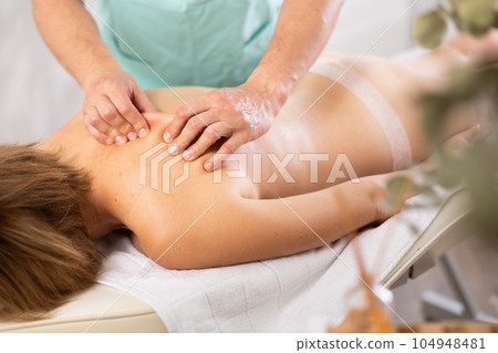 massage therapist doing a back massage massage therapist doing a back massage 104948481
