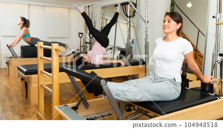 Women doing pilates exercises lying on pilates machines 104948518
