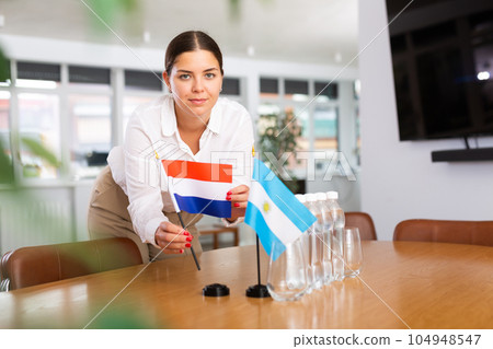 Young lady sets miniatures flags of Argentina and Netherlands for international negotiations 104948547