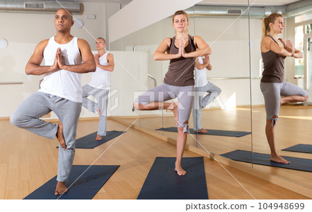 Woman and man standing in balancing pose Eka Pada Pranamasana 104948699