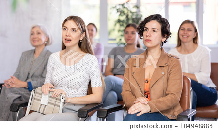 Adult and young women listening to lecture in office Adult and young women listening to lecture in office 104948883