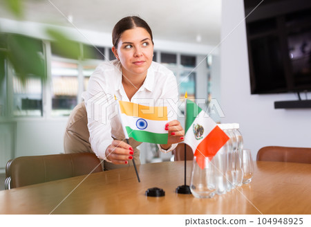 Young lady sets miniatures flags of Mexico and India for international negotiations 104948925