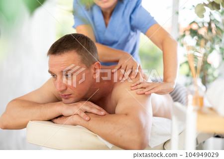 The masseur makes a massage to man 104949029