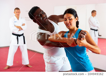 Woman training together with african american man in self defense lessons Woman training together with african american man in self defense lessons 104949162
