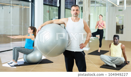 Man standing with pilates ball at gym Man standing with pilates ball at gym 104949227