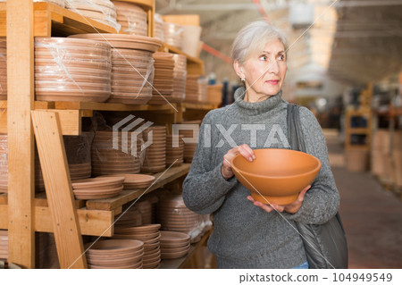 Elderly woman looking for flower pots in hypermarket 104949549
