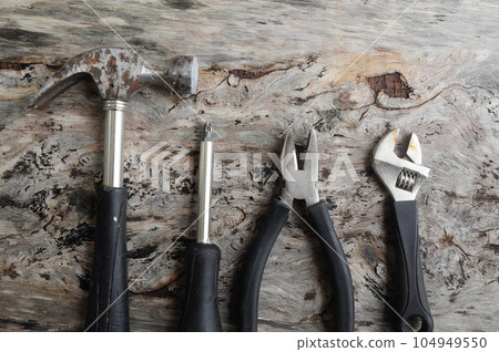 Carpentry hardware that has a black rubber coated handle. Isolated with wood grain backs. 104949550