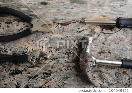 Carpentry hardware that has a black rubber coated handle. Isolated with wood grain backs. 104949551