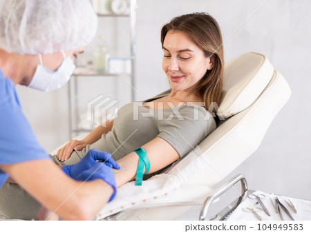 Elderly doctor drawing blood from young patient. Elderly doctor drawing blood from young patient. 104949583