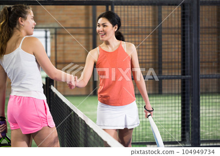 Woman padel player shaking hands to female opponent after match Woman padel player shaking hands to female opponent after match 104949734