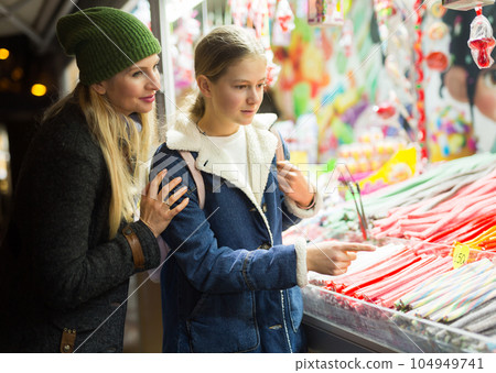 Mother with daughter choosing Christmas sweet and candy at Christmas market in evening Mother with daughter choosing Christmas sweet and candy at Christmas market in evening 104949741