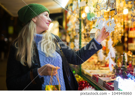 Woman in festive mood choosing Christmas decorations on street fair 104949860