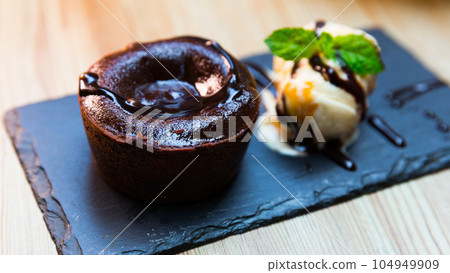 Sweet lava cake served with vanilla ice cream and mint at black plate 104949909