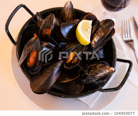 Steamed tasty mussels served on pan with lemon, spanish tapas 104950077