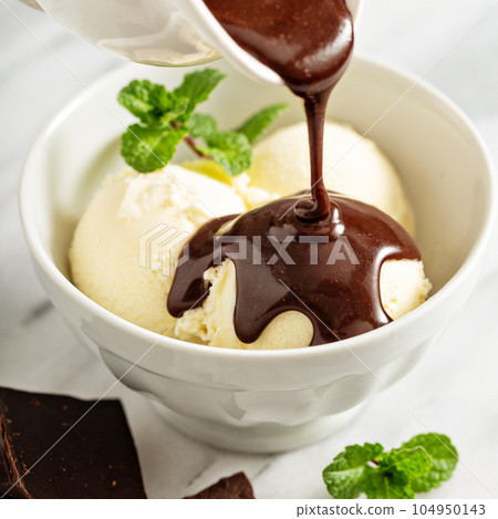 Pouring chocolate sauce on ice cream Pouring chocolate sauce on ice cream 104950143
