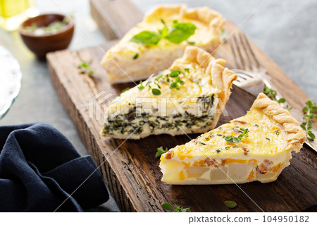 Three quiche pieces on a serving board Three quiche pieces on a serving board 104950182