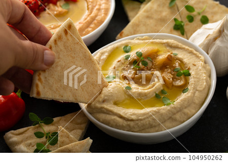 Roasted garlic hummus topped with olive oil Roasted garlic hummus topped with olive oil 104950262