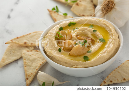 Roasted garlic hummus topped with olive oil Roasted garlic hummus topped with olive oil 104950302