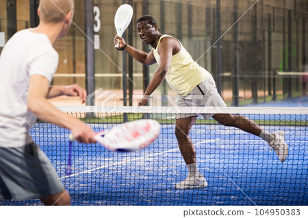 Sporty afro american man playing padel tennis indoor 104950383