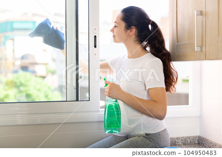 Portrait of young beautiful woman washing windows 104950483