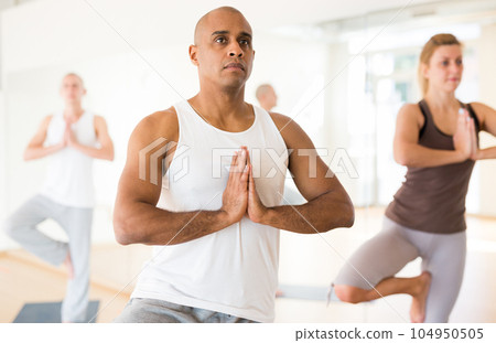 Man making yoga exercises at group class Man making yoga exercises at group class 104950505