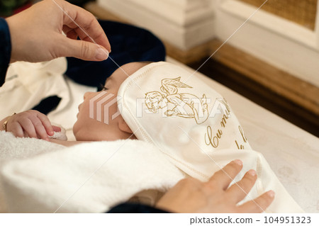 Godmother wraps baby in towel after christening in church 104951323