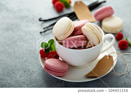 Vanilla and raspberry macarons in a teacup 104951358