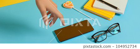 Manicured womans hand with smartphone and stationery over blue table 104952734