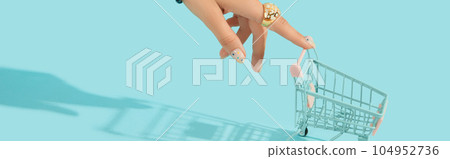 Beautiful groomed womans hand with fashionable ring holding shopping cart on blue background 104952736