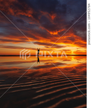 silhouette person against background beautiful sunset sky on ocean, reflection rays sun in water 104952784