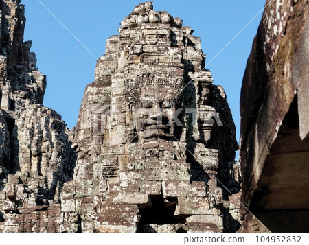 Detailed view of stone human faces adorning the towers of the Bayon Temple, a Khmer site in Cambodia. 104952832
