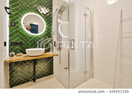 a modern bathroom with green tiles on the wall and white tile flooring around the shower area, there is a mirror in the 104953106