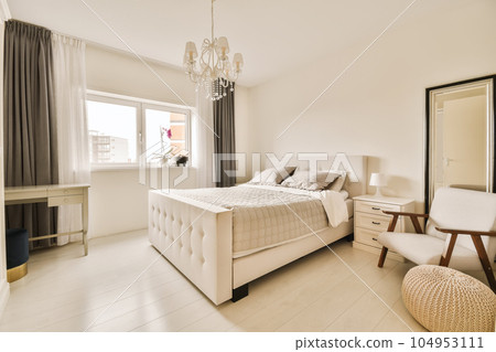 a bedroom with a bed, chair and mirror on the wall in front of the window looking out onto the street 104953111