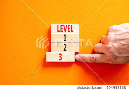 Time to level 3 symbol. Concept word Level 1 2 3 on wooden block. Businessman hand. Beautiful orange table orange background. Business planning and time to level 3 concept. Copy space. 104953168