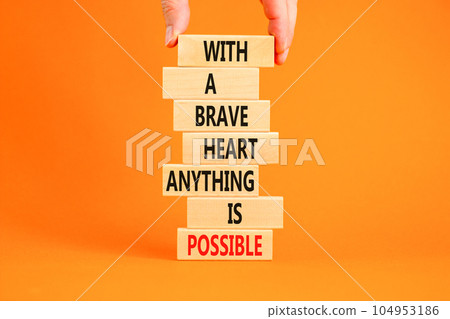 Possible symbol. Concept words With a brave heart anything is possible on wooden blocks on a beautiful orange table orange background. Business motivational brave heart possible concept. Copy space 104953186