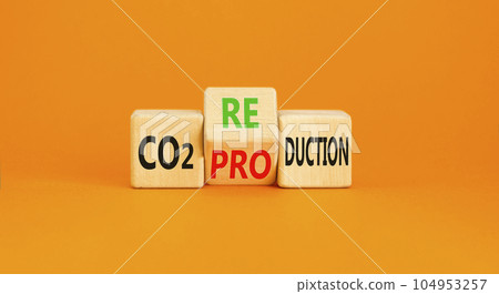 CO2 production or reduction symbol. Concept word CO2 production reduction on a wooden block on a beautiful orange background. Business ecological and CO2 changes concept. Copy space. 104953257