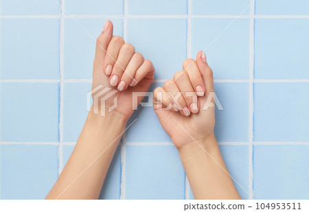 Beautiful womans hands with nude nail design on blue background. Manicure, pedicure beauty salon concept Beautiful womans hands with nude nail design on blue background. Manicure, pedicure beauty salon concept 104953511