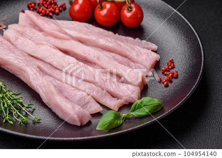 Raw chicken or turkey fillet cut into strips with spices and herbs Raw chicken or turkey fillet cut into strips with spices and herbs 104954140