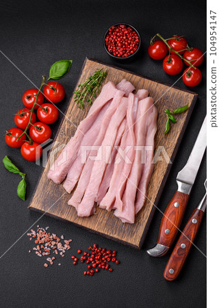 Raw chicken or turkey fillet cut into strips with spices and herbs 104954147