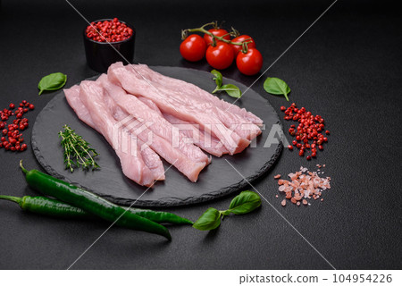Raw chicken or turkey fillet cut into strips with spices and herbs 104954226