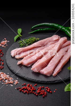 Raw chicken or turkey fillet cut into strips with spices and herbs 104954241