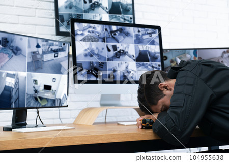 Male security guard sleeping near monitors at workplace 104955638