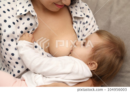 Woman breastfeeding her little baby at home, closeup 104956003