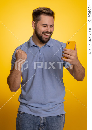 Happy excited winner young man use smartphone say wow yes found out great big win good news lottery Happy excited winner young man use smartphone say wow yes found out great big win good news lottery 104956064