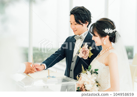Bride and groom signing a marriage certificate / marriage vow at a wedding ceremony Bride and groom signing a marriage certificate / marriage vow at a wedding ceremony 104958659
