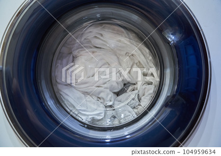 Close-up shows how the laundry is washed in an isolated washing machine. The concept of household appliances. High quality photo 104959634